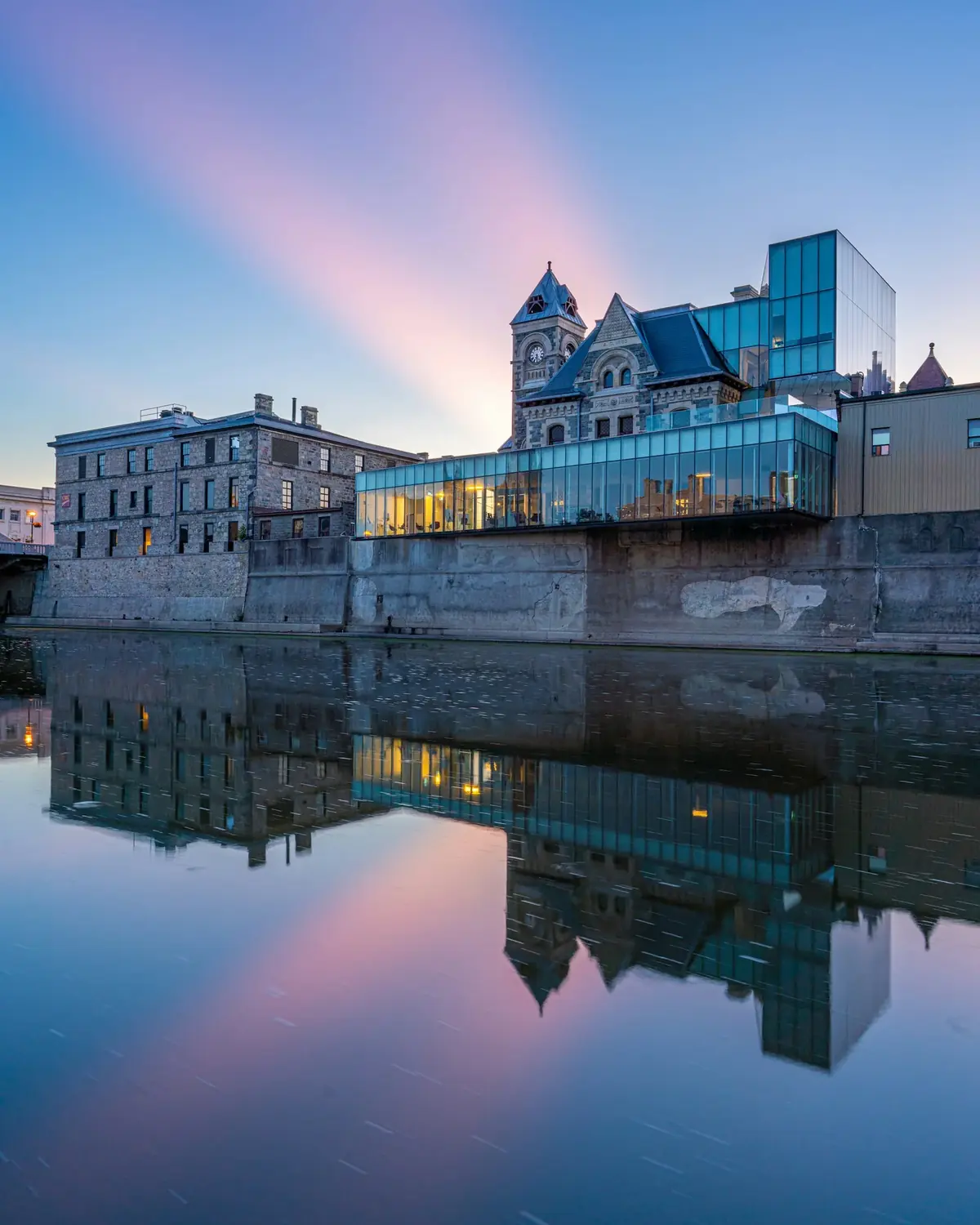 Historic stone mill and the Galt Post Office clock tower reflected in the Grand River in Cambridge, Ontario