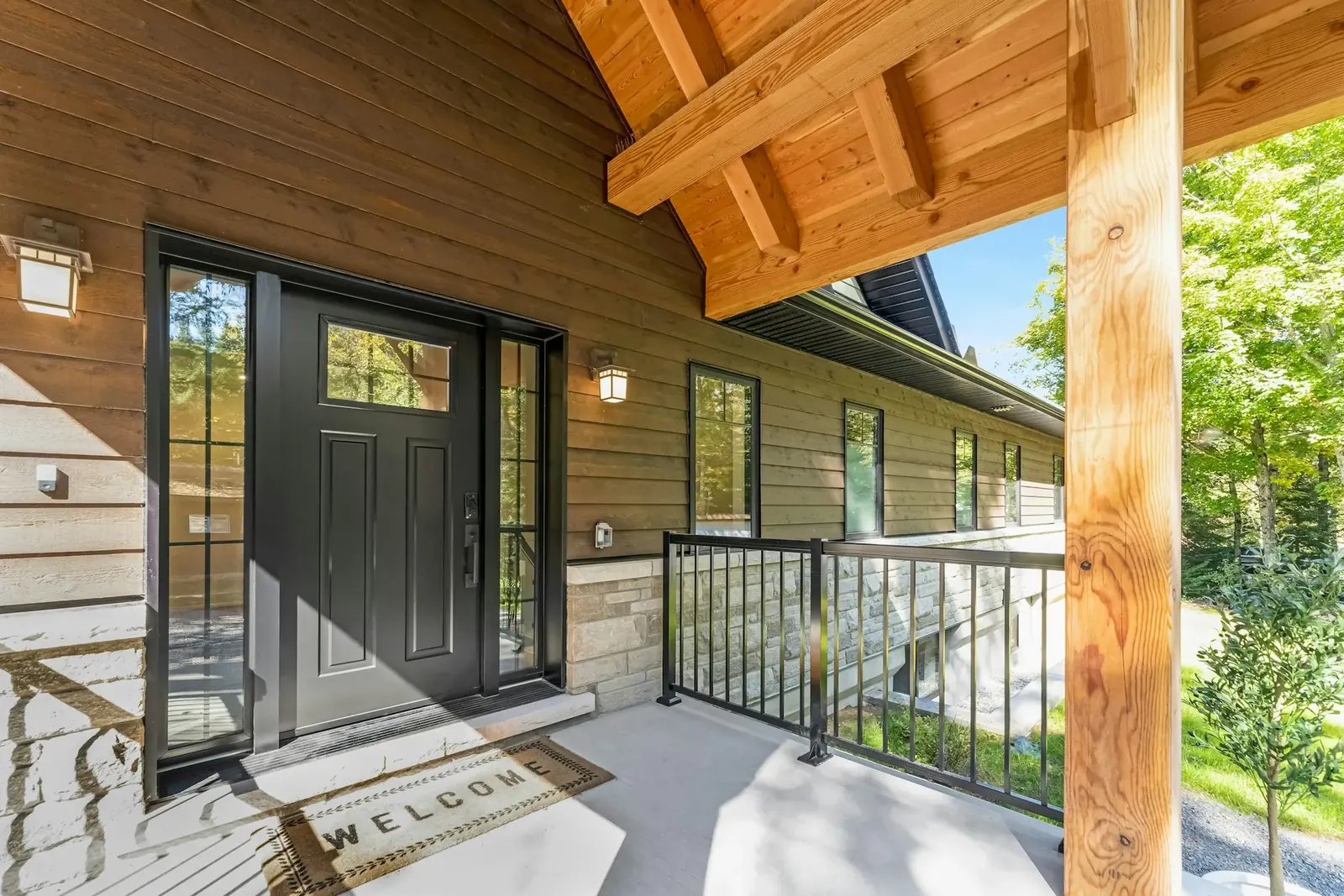 Covered front porch of a wood-sided home with a welcome mat