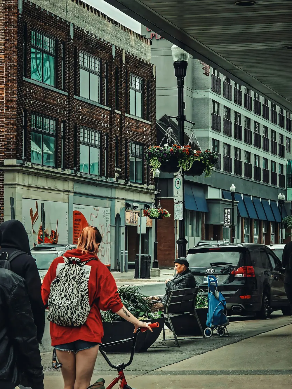 Pedestrians passing brick storefronts and hanging flower baskets on King Street in downtown Kitchener