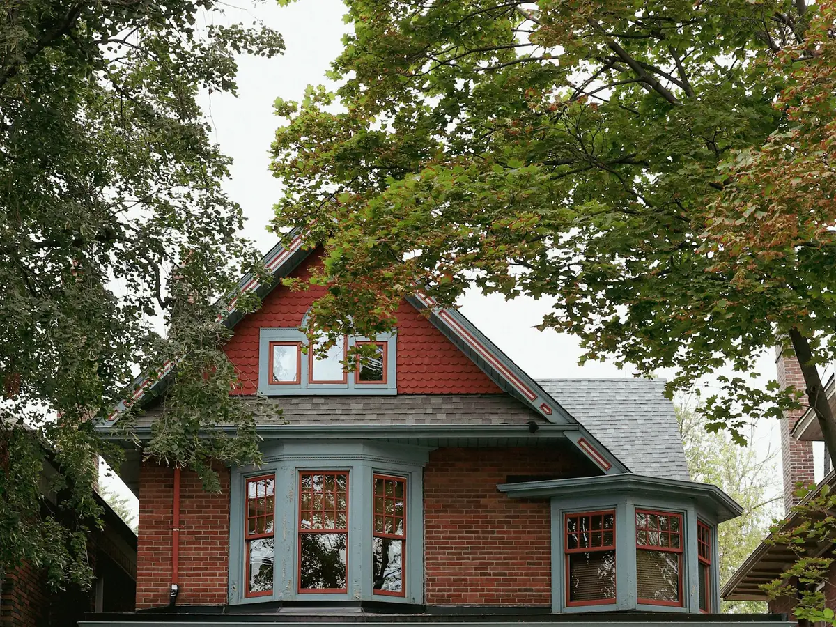 Red-brick family home with a deep front porch and bay windows on a leafy street